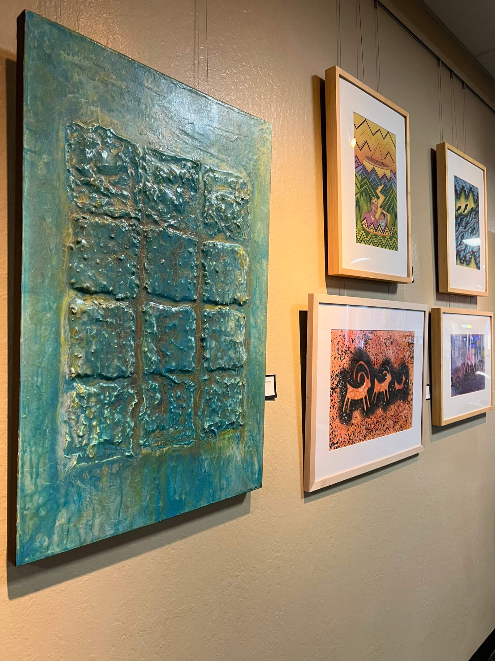 Exhibition wall from Stewart Indian School exhibition. Pieces include a composition with a square pattern and illustrations.