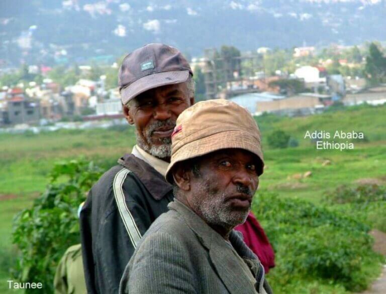 Two men posing for a photo with town in the background.