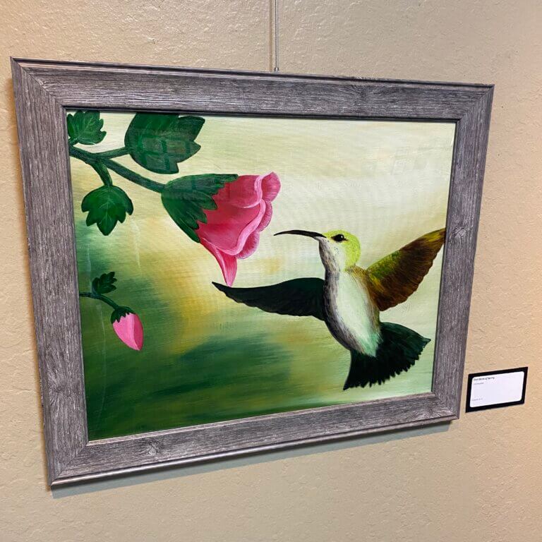 Photo of a framed painting depicting a hummingbird and a flower.