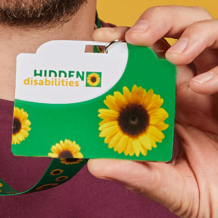 Close up of man holding Hidden Disabilities lanyard.