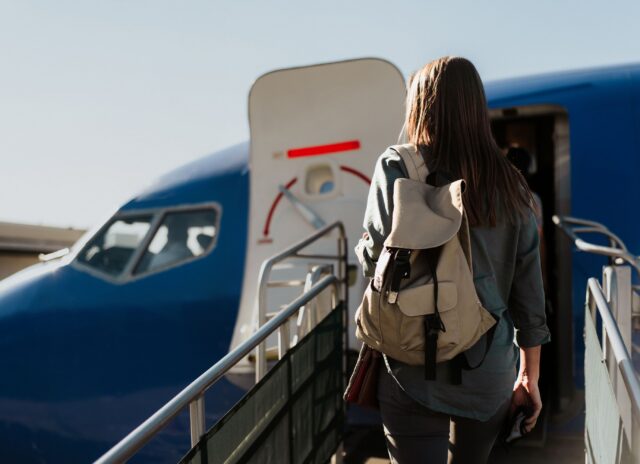 Exterior photo of a woman boarding a plane on a sloped ramp