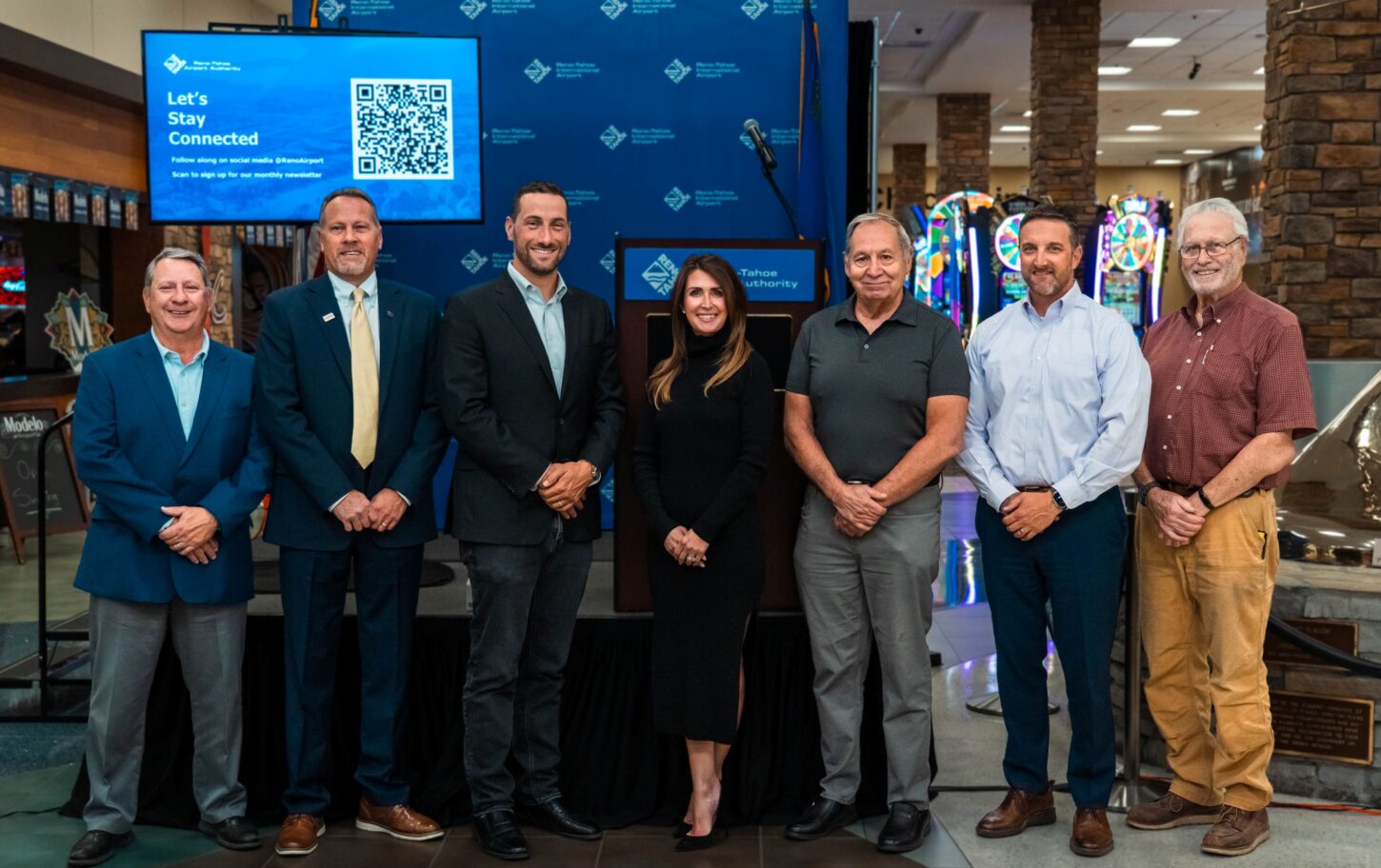 RTAA board of trustees stand with RTAA president and CEO Cris Jensen in front of a stage in the Reno-Tahoe International Airport terminal