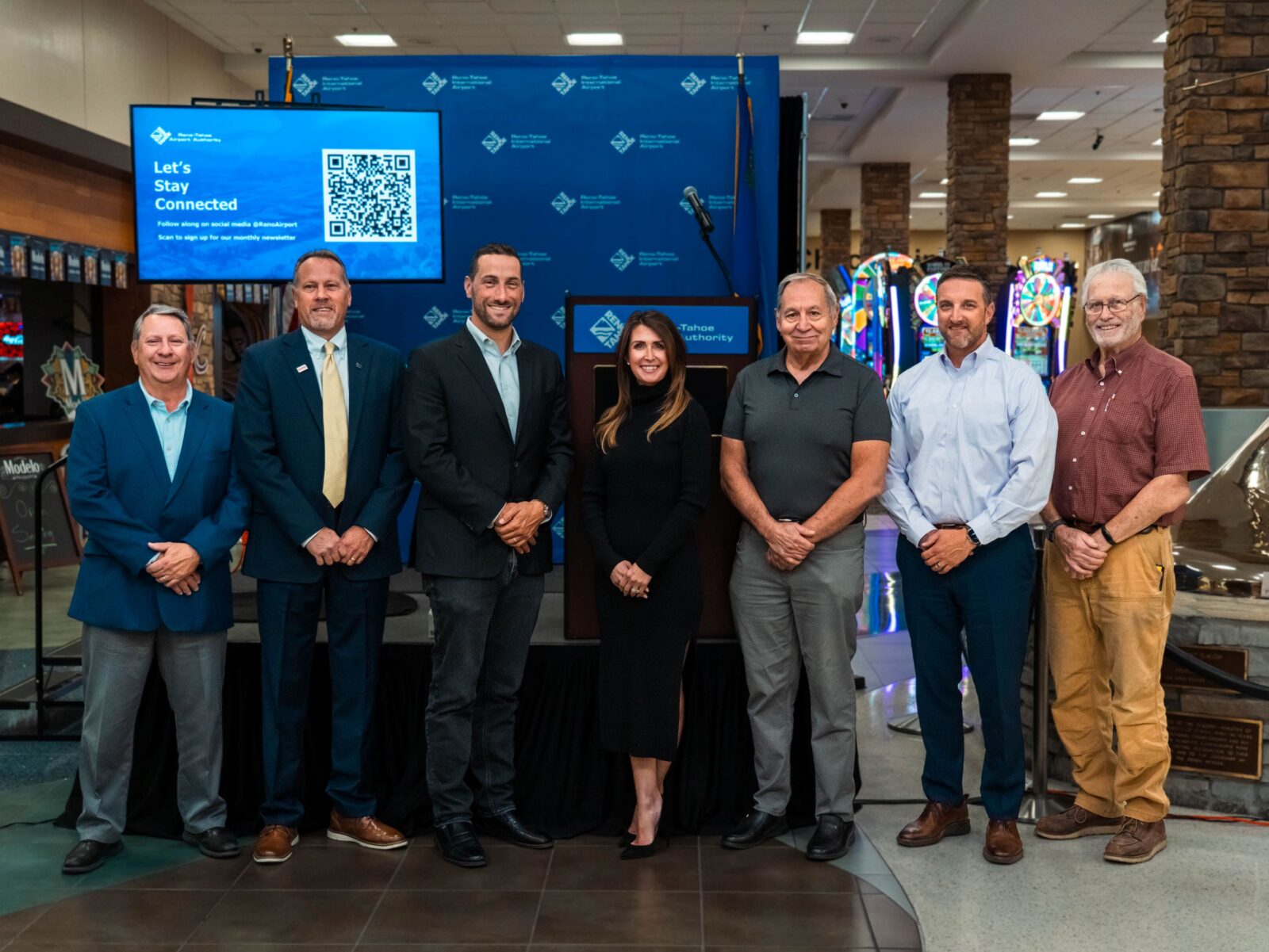 RTAA board of trustees stand with RTAA president and CEO Cris Jensen in front of a stage in the Reno-Tahoe International Airport terminal