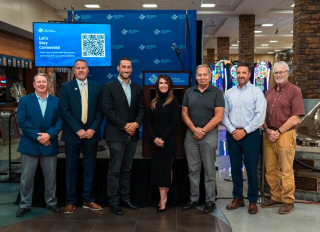 RTAA board of trustees stand with RTAA president and CEO Cris Jensen in front of a stage in the Reno-Tahoe International Airport terminal